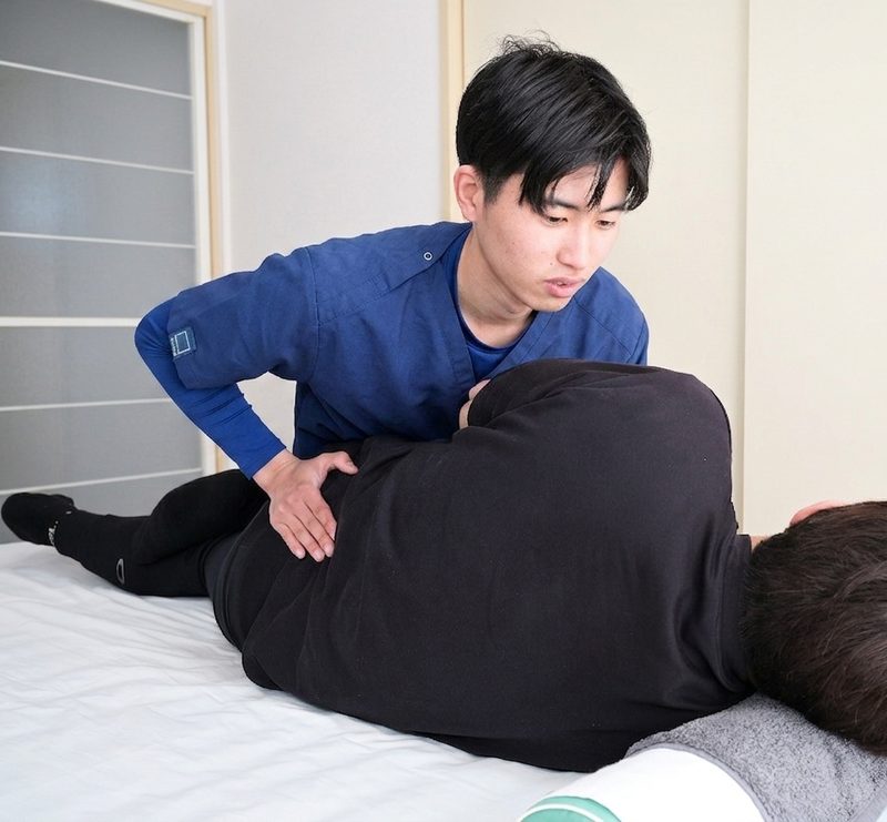 横向きで骨盤まわりを確認する施術の様子